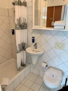 فندق برو ميسي هانوفر في هانوفر: حمام ابيض مع مرحاض ومغسلة