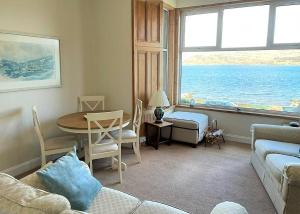 a living room with a couch and a table with a view of the ocean at Kames View Apartment in Tighnabruaich