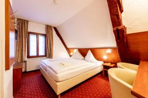 ヴァイセンフェルスにあるRinghotel Jägerhofのベッドと椅子付きのホテルルーム