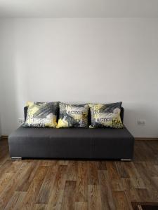 a black couch with pillows on a wooden floor at Pokój przy jeziorze in Wiżajny