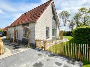 ein kleines weißes Haus mit einem Holzzaun in der Unterkunft Hello Zeeland - Vakantiehuis Stern 218 in Breskens