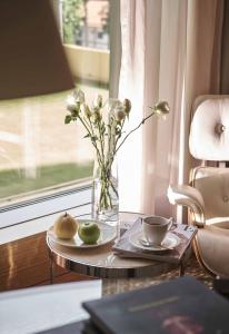 a vase with flowers and apples on a table with a window at InterContinental Saigon, an IHG Hotel in Ho Chi Minh City