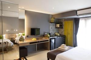 a bedroom with a bed and a desk with a television at Ploen Chaweng by Tolani in Chaweng