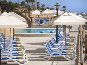 a group of chairs and umbrellas next to a pool at Marina Hotel Corinthia Beach Resort Malta in St. Julianʼs