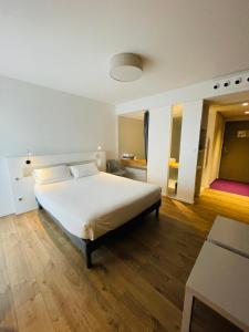 - une chambre avec un grand lit blanc et du parquet dans l'établissement Hotel Restaurant Santiago, à Hendaye