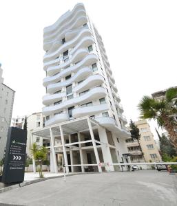 a large white building with palm trees in front of it at Sky Garden Suites in Adana