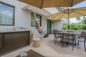 Un patio con una mesa y sillas y una sombrilla. en Ecolife Térreo, jardim privativo e churrasqueira, en Porto de Galinhas