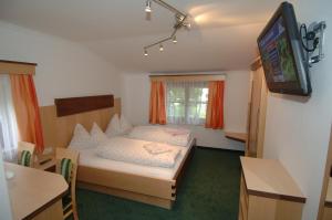 a small room with a bed and a television at Gästehaus Ingeborg in Saalbach-Hinterglemm