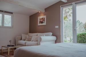 a bedroom with a bed and a couch and a window at Chambres d'hôtes Villa Cardabella in Le Tignet