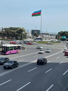un bus rose circulant sur une autoroute avec un drapeau dans l'établissement Azneft Royal Suite Apartment Sea View, à Baku