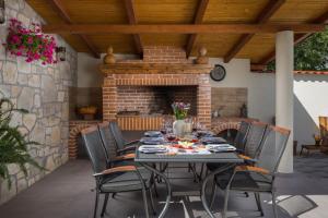 a table and chairs on a patio with a fireplace at Villa Giardino in Drinovci