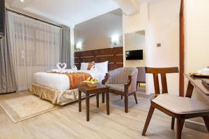 ein Hotelzimmer mit einem Bett und einem Tisch und Stühlen in der Unterkunft The Kyaka Hotel in Machakos
