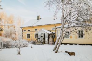 Una gran casa amarilla con nieve en el suelo en Salaisen Puutarhan Majatalo, en Kauhajoki