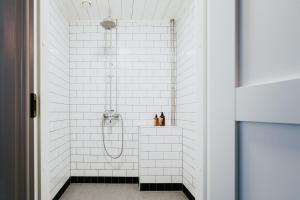 a bathroom with white subway tiles and a shower at Salaisen Puutarhan Majatalo in Kauhajoki