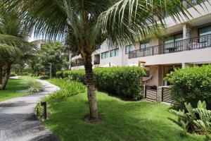 una palmera delante de un edificio en Ecolife Térreo, jardim privativo e churrasqueira, en Porto de Galinhas
