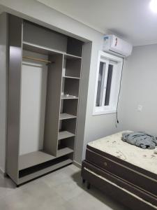 a bedroom with a bed and a book shelf at NOVO LAR GAROPABA 2 in Garopaba