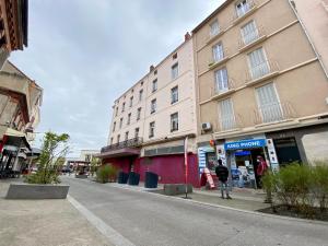 a person standing in front of a building on a street at Le Tropical #Confort#Proche Gare in Clermont-Ferrand