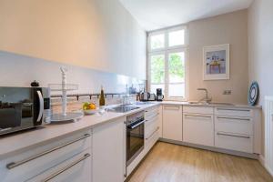 Una cocina grande con gabinetes blancos y una ventana. en Villa Brunnenstraße, App 2, en Heringsdorf