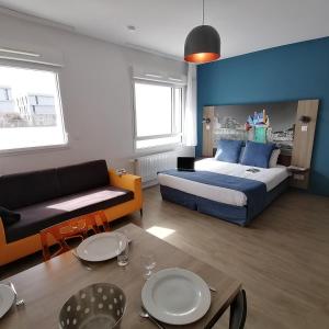 1 dormitorio con cama, sofá y mesa en Appart-Hotel Mer & Golf City Ile de Nantes en Nantes