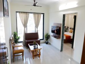 een woonkamer met een bank, een bed en een spiegel bij Hotel Satyam Residency in Navi Mumbai
