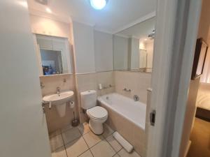 a bathroom with a toilet and a tub and a sink at Santos 49 in Mossel Bay