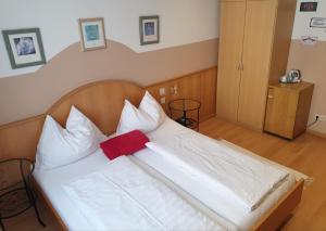 a large white bed with a red pillow on it at Hotel Pension Alte Mühle in Klosterneuburg