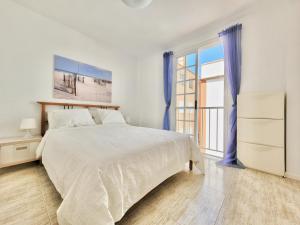 Dormitorio blanco con cama y ventana grande en Playa Arena Apartment, en Araya