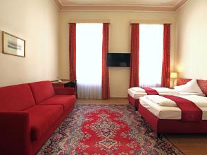 Una habitación de hotel con dos camas y un sofá rojo. en HPA Hotel Andreas, en Viena