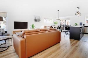 a living room with a brown couch and a kitchen at 15 Chemin des Cascades in Stoneham