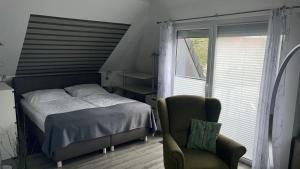 a bedroom with a bed and a chair and a window at Haus-Encore-Wohnung-2 in Büsum