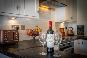 a bottle of wine and two wine glasses on a kitchen counter at The Old Cattle Barn - Splendid Yorkshire getaway in Todmorden +16 photos