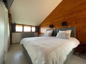 - une chambre avec un grand lit et un mur en bois dans l'établissement Les Perruchons ancienne grange rénovée avec soin, à Ozolles