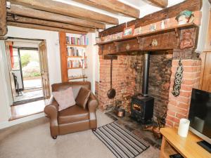 uma sala de estar com uma cadeira e uma lareira de tijolos em Apple Tree Cottage em Evesham