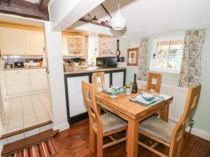 uma cozinha e sala de jantar com uma mesa de madeira e cadeiras em Apple Tree Cottage em Evesham