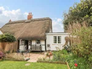 a thatched cottage with a patio and garden at Apple Tree Cottage in Evesham