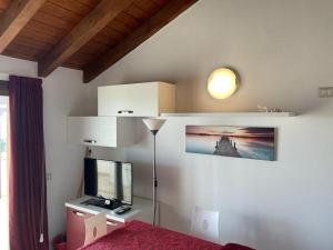 Zimmer mit einem Bett, einem TV und einer Lampe in der Unterkunft Residence L'Incanto Attici in Castelsardo