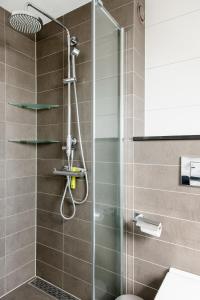 a shower with a glass door in a bathroom at Julianadorp Zuhause am Meer für 6 Personen mit 4 Schlafzimmern in Julianadorp