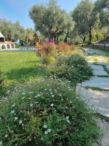 un jardín con flores y un parque infantil al fondo en Moses Villa en Chorefto