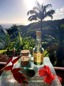 a bottle of wine sitting on a table with a flower at Gîte 4 étoiles, la Vieille Sucrerie St Claude Guadeloupe, Jacuzzi Spa privatif, vue exceptionnelle sur la mer des Caraïbes in Basse-Terre