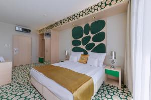 um quarto com uma cama grande e uma cabeceira verde em Hotel Aurum Family "A" em Hajdúszoboszló