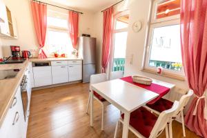 a kitchen with a white table and chairs and windows at Ferienwohnung Jenzigblick in Jena