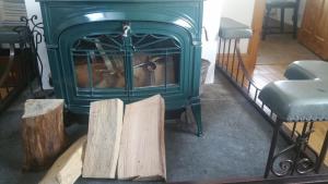 a green woodburning stove with some logs in front of it at Tomnagairn Cottage in Dunkeld