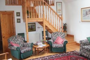 a living room with two chairs and a staircase at Tomnagairn Cottage in Dunkeld