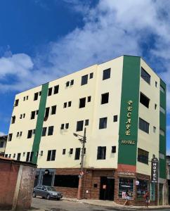 a white and green building with a car in front of it at Pecafe Hotel in Manhuaçu