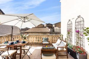 un patio con tavoli, sedie e ombrellone di Guest House Aurispa a Noto