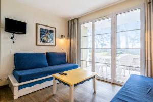 フエナンにあるResidence Cap Azur - maeva Homeのリビングルーム(青いソファ、テーブル付)