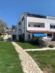 a building with a stone path in front of a yard at Seaside apartments Petar in Krk