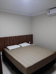 a bedroom with a large bed with a wooden headboard at VIA CALDAS DIROMA PIAZZA in Caldas Novas
