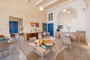 a dining room with tables and chairs and a kitchen at Georges Boutique Living in Xagħra