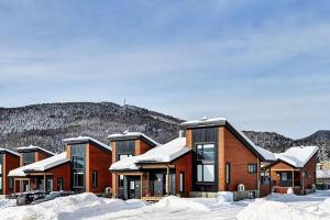 una fila de casas en la nieve con montañas en el fondo en 106 Chemin des Ruisselets, en Stoneham